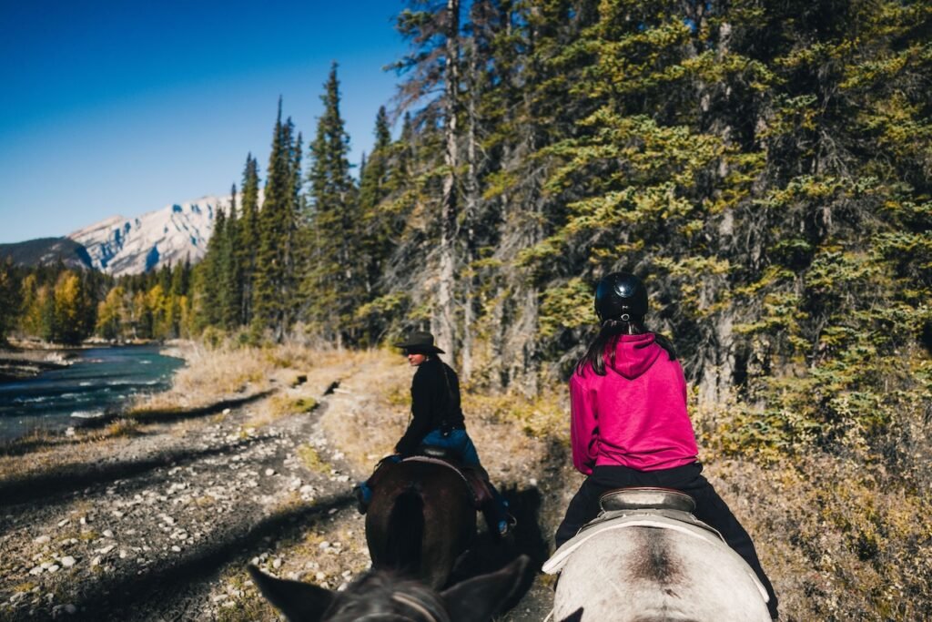 Group of riders on horseback following a scenic forest trail during a Banff Trail Riders experience in Banff National Park