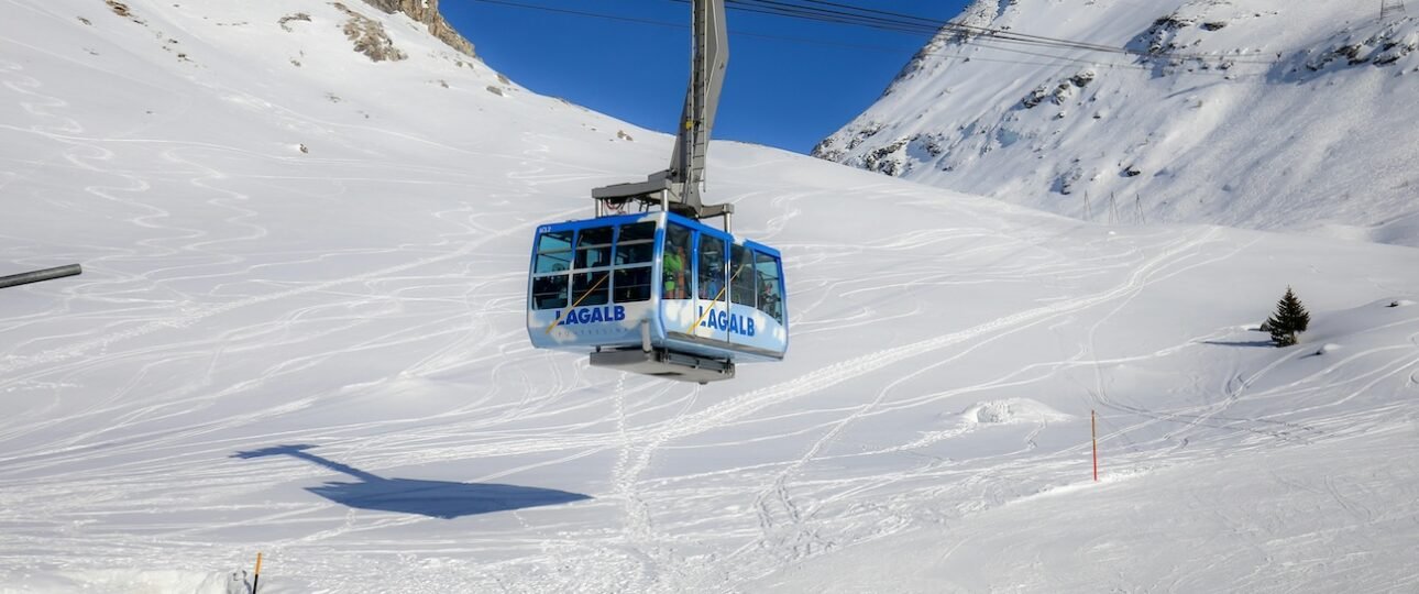 Skier on a groomed run at Lake Louise Ski Resort in the Canadian Rockies, Alberta, with snow-covered mountain peaks and blue sky in the background