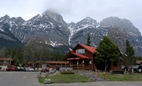 Aerial view of the Fairmont Banff Springs hotel surrounded by autumn forest and snow-capped Rocky Mountain peaks in Banff National Park, Alberta
