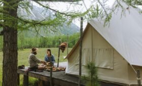 Lit geodesic dome tent glowing warmly against a star-filled night sky in the Canadian Rockies near Jasper National Park, Alberta, Canada