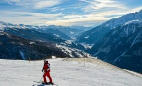 Split view of skiers on the open alpine terrain at Sunshine Village and the forested runs at Lake Louise ski resort, Banff National Park, Alberta, Canada