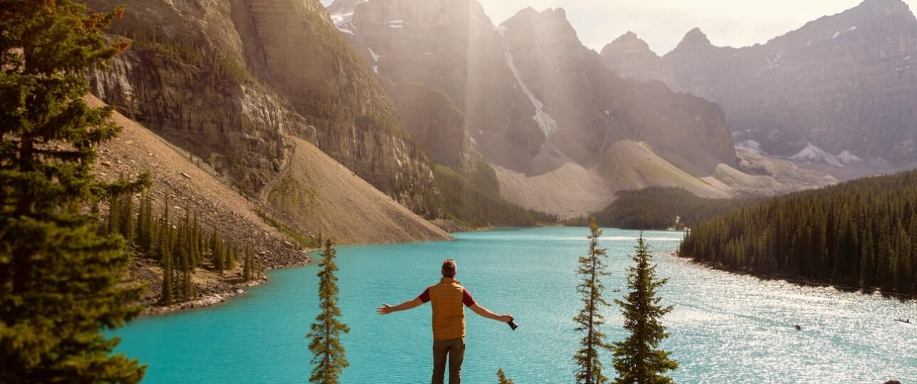 Hiker standing at Sentinel Pass above Larch Valley with golden larch trees, turquoise Moraine Lake, and the Valley of Ten Peaks in the background, Banff National Park, Alberta